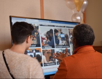 S-LTA Alex Spak and Adreene Law from Timothy Smith Network look at photos of students Robotics projects